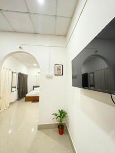 a white room with a bed and a tv on a wall at Heritage Home in Guwahati