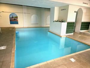 a swimming pool with blue water in a building at Abbey Sands Hotel in Torquay