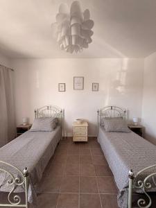 a bedroom with two beds and a chandelier at Cascina Tesoriera in Santhià