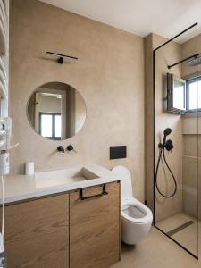 a bathroom with a sink and a toilet and a mirror at Trigono Suites - Karat in Politika +9 photos