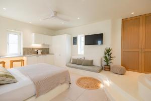 a white bedroom with a bed and a kitchen at Naxia Gaia Suites in Agia Anna Naxos