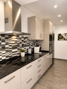 a kitchen with white cabinets and black counter tops at Villa Cambrils Mar in Cambrils