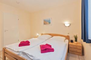 a bedroom with a white bed with red towels on it at Haus Roland, Wohnung 04 in Zinnowitz