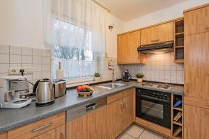 a kitchen with wooden cabinets and a sink and a window at Haus Roland, Wohnung 04 in Zinnowitz
