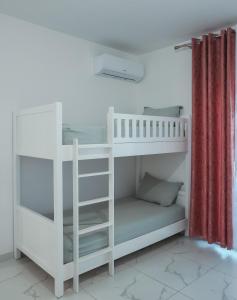 a white bunk bed in a room with a red curtain at EBIS HOTEL in Shëngjin