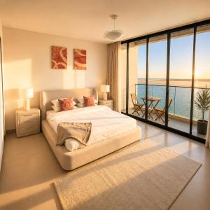 a bedroom with a bed with a view of the ocean at Ajmal Villa in Al Ḩamrīyah +52 photos