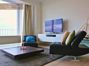 a living room with a couch and a tv at Le Channel - Parenthèse calme face à la mer sur la digue - Idéal famille - Équipements bébé - Ascenseur in Koksijde