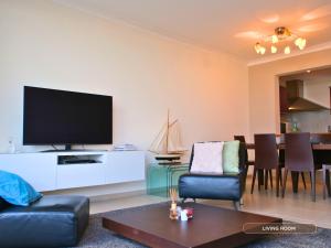 a living room with a flat screen tv on a white cabinet at Le Channel - Parenthèse calme face à la mer sur la digue - Idéal famille - Équipements bébé - Ascenseur in Koksijde +17 photos