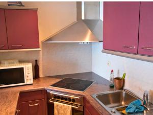 a kitchen with a sink and a stove and a microwave at Le Channel - Parenthèse calme face à la mer sur la digue - Idéal famille - Équipements bébé - Ascenseur in Koksijde