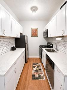 a kitchen with white cabinets and a sink and a refrigerator at Downtown Houston Studio - Walk to Toyota Center in Houston