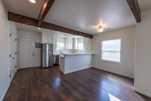an empty living room with a kitchen and wooden floors at Park Street Apartment - Front Unit in Paso Robles