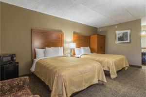 a hotel room with two beds and a tv at GreenRidge Hotel in Wickliffe