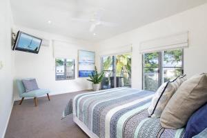 a bedroom with a bed and a chair and windows at Tranquil & Modern Riverside Getaway in Noosaville