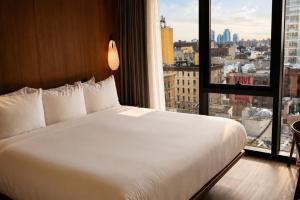 a bed in a hotel room with a large window at Merchant LES Hotel in New York +36 photos