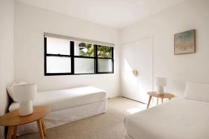 a white bedroom with a bed and a window at Casa Six on Witta in Noosa Heads