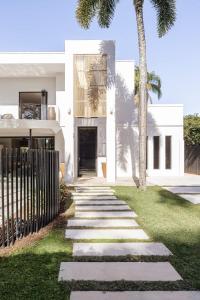 a walkway in front of a white house with palm trees at Casa Six on Witta in Noosa Heads +33 photos
