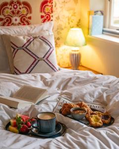 a tray of breakfast foods and a book on a bed at The Pear Tree Inn in Bury Saint Edmunds