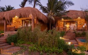 a house with a thatched roof and stairs at Palm Grove Beach Resort in Mandrem