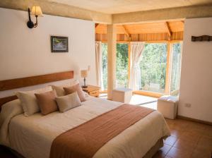 a bedroom with a large bed and a large window at Cabañas Rucaleufu in San Martín de los Andes +40 photos