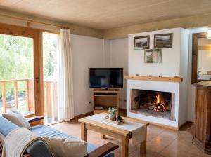 a living room with a fireplace and a tv at Cabañas Rucaleufu in San Martín de los Andes