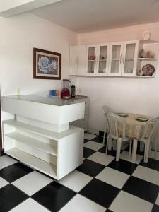 a kitchen with white cabinets and a black and white checkered floor at Apartamento in Natal +11 photos