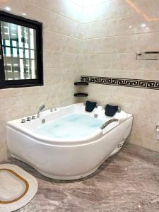 eine große weiße Badewanne in einem Badezimmer mit Fenster in der Unterkunft Tijania Complex in Bijilo + 17 Fotos