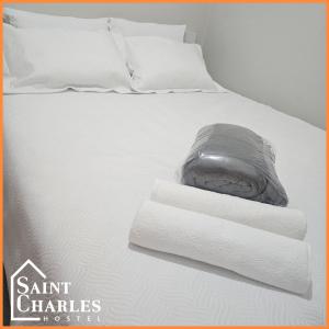 a bed with white sheets and towels on it at Saint Charles Hostel in São Carlos