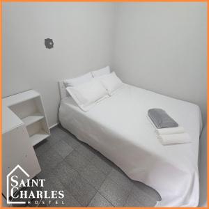 a white bedroom with a large bed with white sheets and pillows at Saint Charles Hostel in São Carlos +26 photos