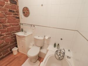 a bathroom with a toilet and a sink and a bath tub at The Hayloft in Wigton
