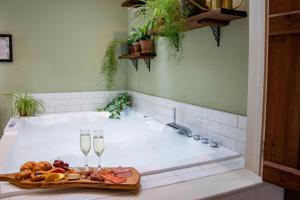 a bath tub with a tray of food and two glasses of wine at The Pear Tree Inn in Bury Saint Edmunds