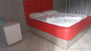 a red bed with white sheets and a red headboard at Hotel 1001 noites samambaia ADE in Brasília