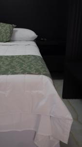 a bed with white sheets and a green comforter at Hotel Makao in La Rosita