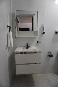 a white bathroom with a sink and a mirror at Hotel Makao in La Rosita