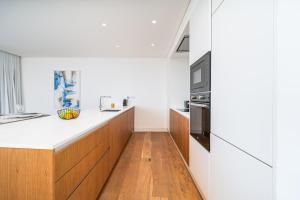 a kitchen with white countertops and wooden cabinets at Vilamoura 4-Bedroom Penthouse with Jacuzzi in Vilamoura +18 photos
