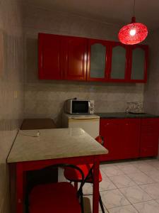 a kitchen with red cabinets and a table with red chairs at Hotel Dona in Mamaia