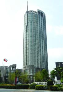 un edificio de cristal alto con una bandera delante de él en Royal Palace Hotel Haining, en Haining