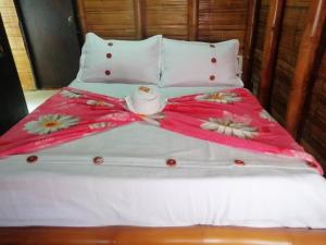 a bed with a pink blanket with flowers on it at Hostal El Bambú in Inzá