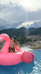 a woman riding on an inflatable pink flamingo in the water at Hotel Luxor Selva in La Merced