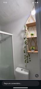 a bathroom with a toilet and a shelf with plants at Pouso do Caiçara suíte in Paraty