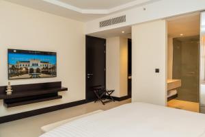a bedroom with a bed and a tv on the wall at Lancaster Palace Tamuda Bay in Marina Smir