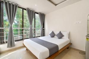 a bedroom with a bed and large windows at Hotel Sawaastic in Calangute North GOA in Calangute