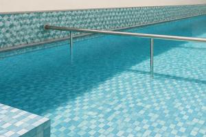 a swimming pool with a metal rail in the water at Hotel Sawaastic in Calangute North GOA in Calangute