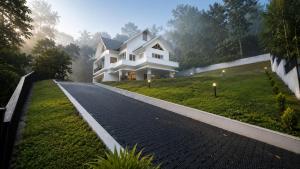 a white house on a hill with a driveway at Trinity Villa Home Stay in Idukki