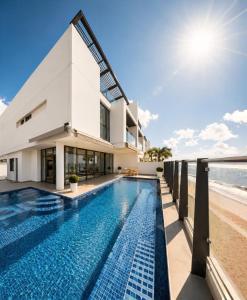 a house with a swimming pool next to the beach at Ajmal Villa in Al Ḩamrīyah