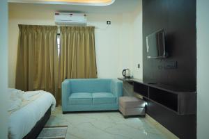 a bedroom with a bed and a blue chair and a tv at Hotel Delw in Bacha