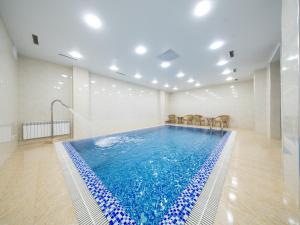 a swimming pool with chairs in a room at Grand Capital Hotel in Tashkent