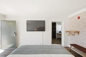 a bedroom with a bed and a flat screen tv on the wall at Sunset Motel in Santa Barbara