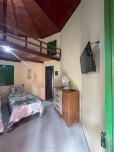 a bedroom with a bed and a tv in a room at Chalé Raio De Sol in Vale do Capao