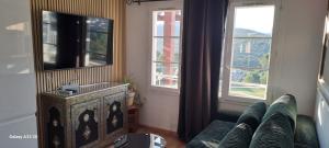 a living room with a tv and two windows at Cap Esterel vue Mer in Agay - Saint Raphael