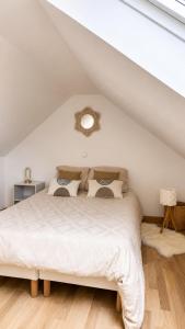 a bedroom with a white bed in a attic at Joli triplex proche Colmar in Sainte-Croix-en-Plaine